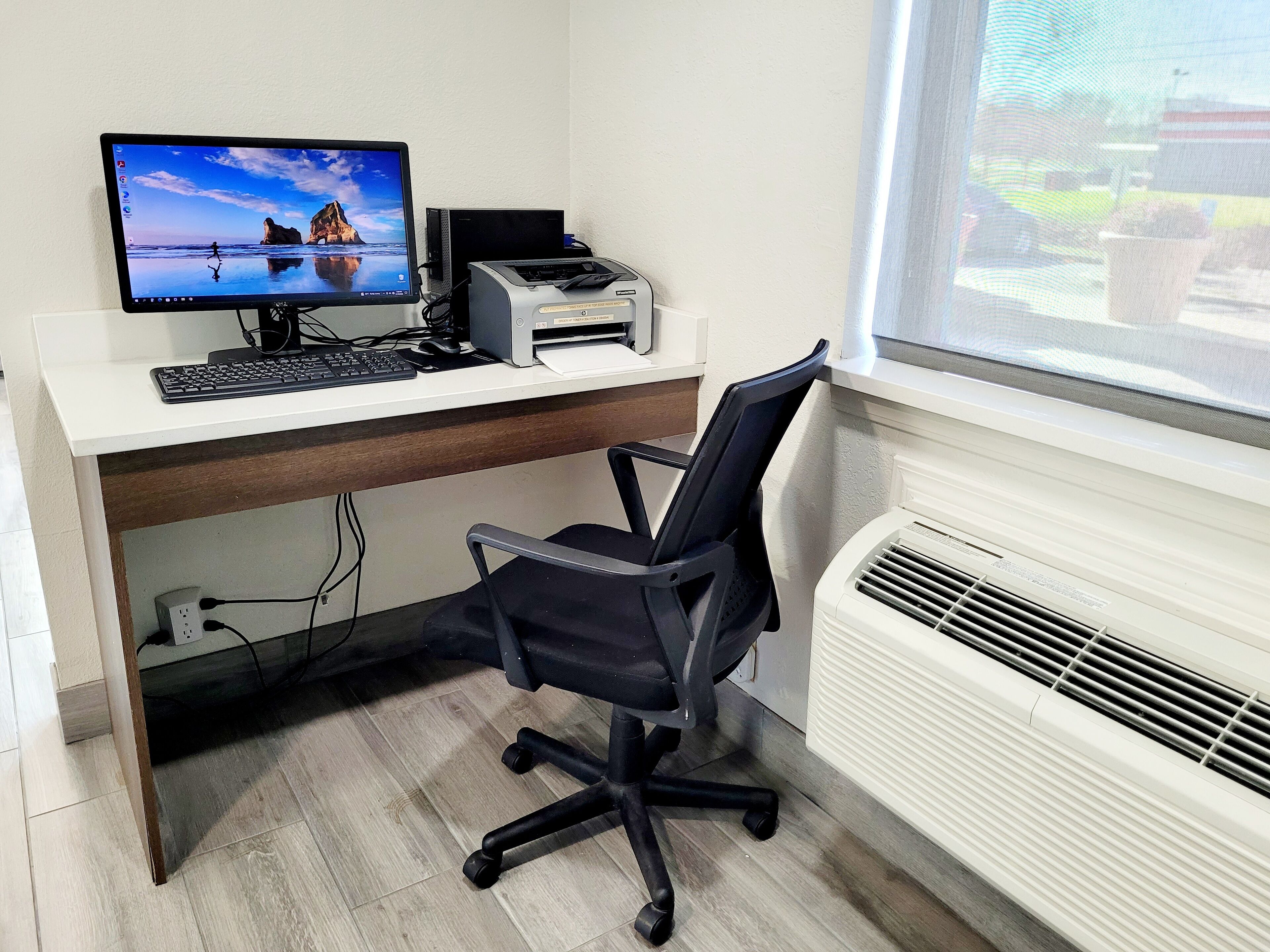 A home office setup with a desktop computer, printer, and office chair.