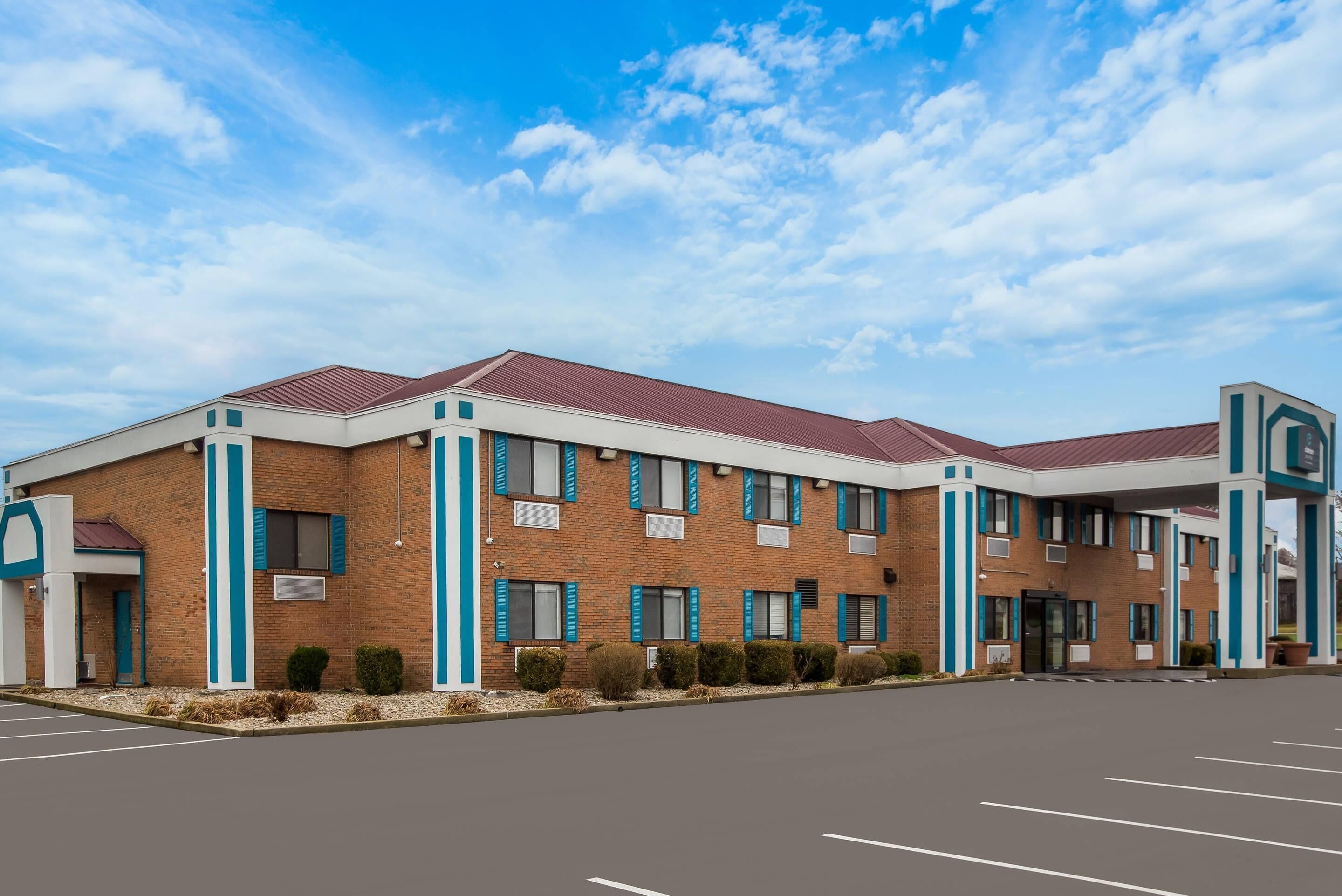 A multi-story hotel with a brick facade, blue accents, and a parking lot.
