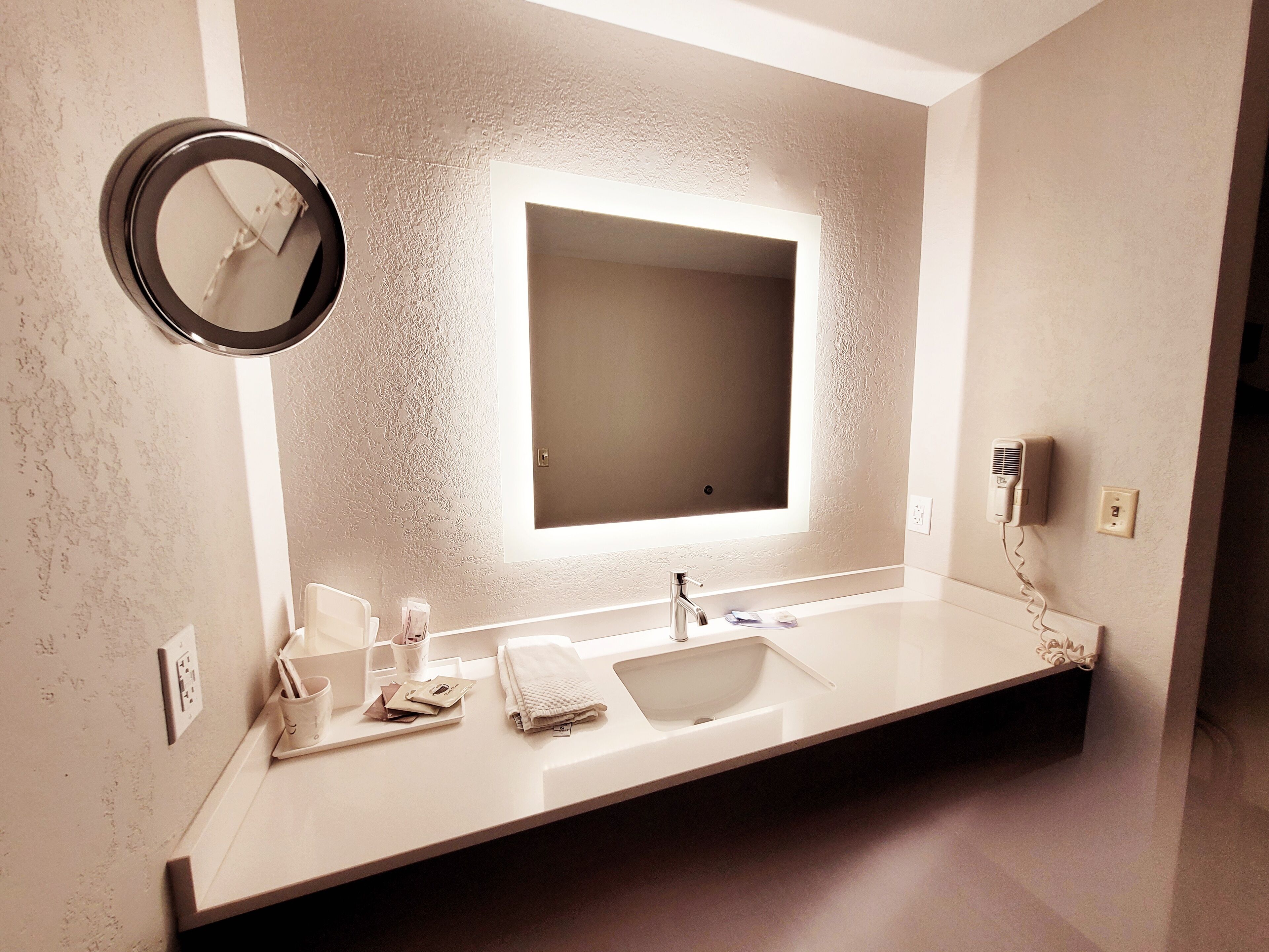 A modern bathroom with a large mirror, a sink, and a towel rack.