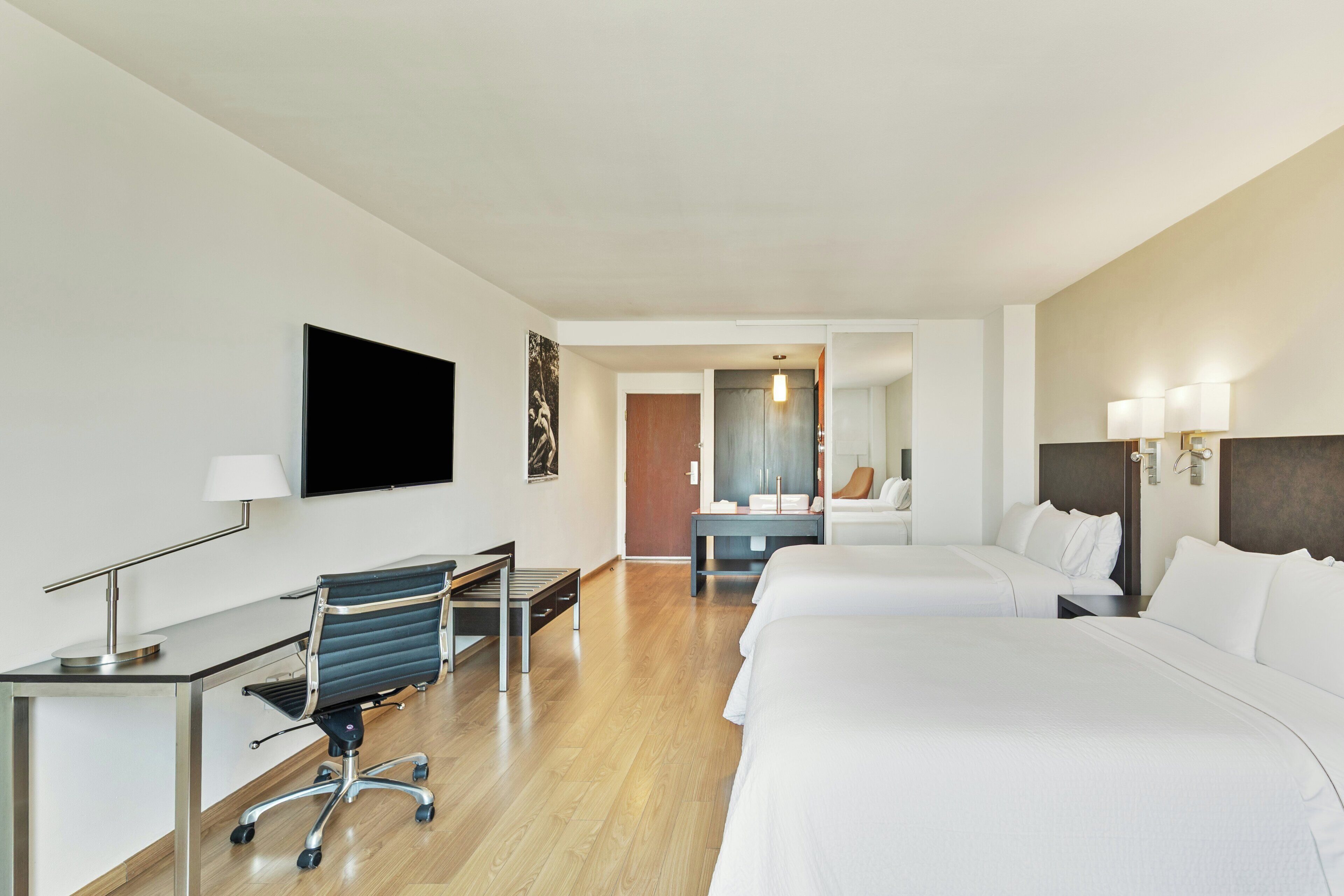 Ein Hotelzimmer mit Bett, Schreibtisch, Stuhl und Fernseher.