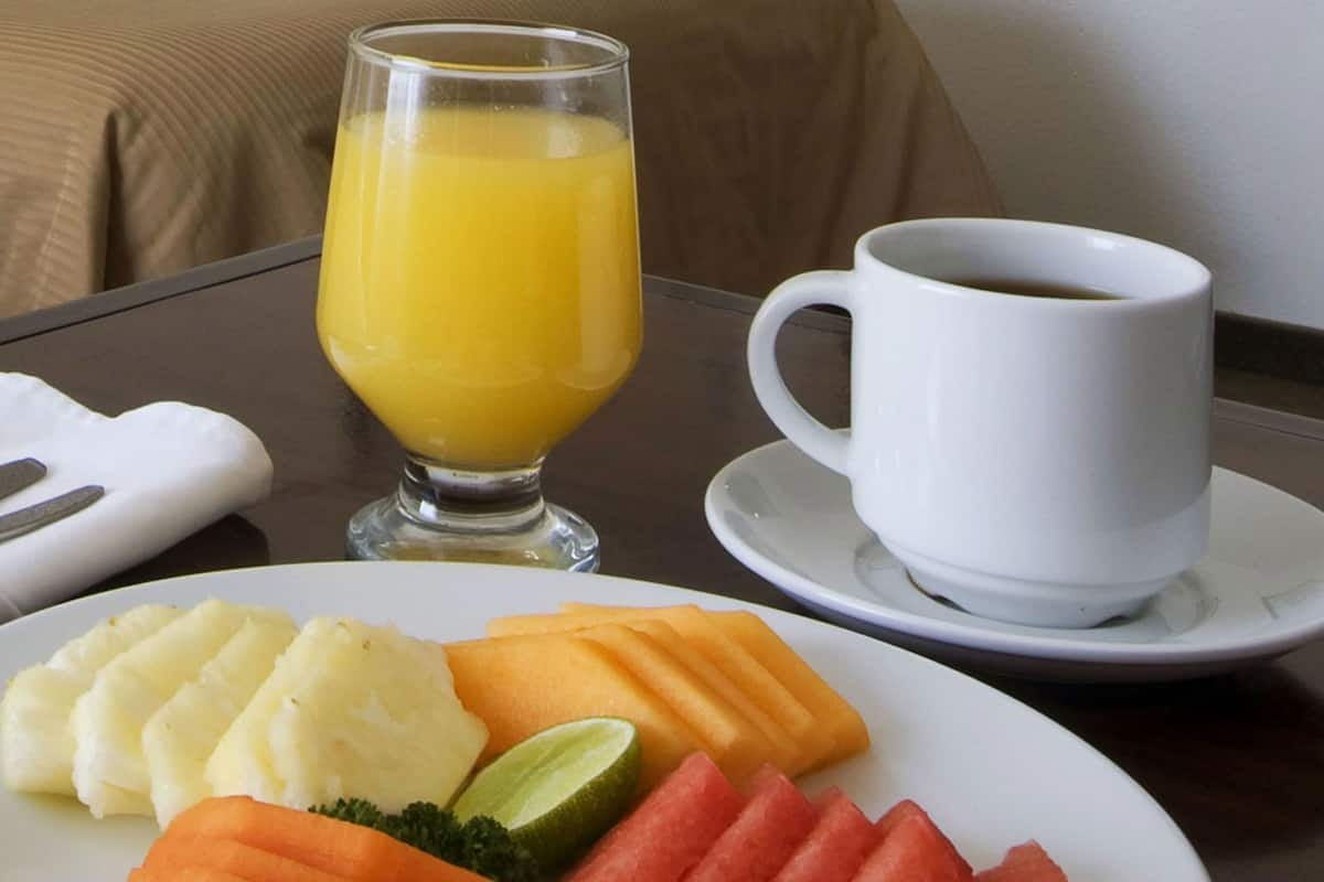 A breakfast setting with a plate of food, a glass of orange juice, and a cup of coffee on a table.