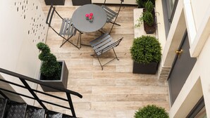 A rooftop terrace with a round table and chairs, surrounded by potted plants. - Hotel Riviera Elysées (Paris)