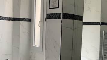 A modern bathroom with a large bathtub, a sink, and a shower area.