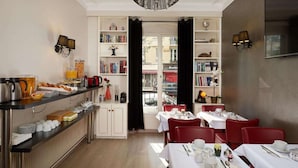 A dining area with tables set for breakfast, a coffee station, and bookshelves.