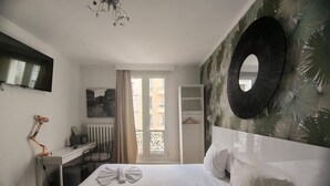 A hotel room with a bed, a desk, a chair, a TV, and a large mirror.
