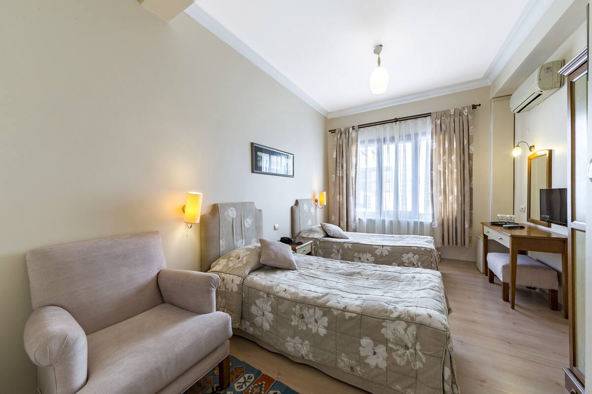 A hotel room with two beds, a sofa, a desk, and a mirror.