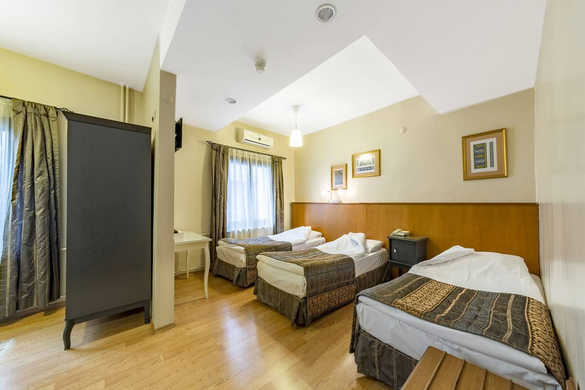 A hotel room with two single beds, a desk, a chair, a wardrobe, and a ceiling light.