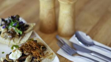 A plate with food items and a set of cutlery on a wooden table.