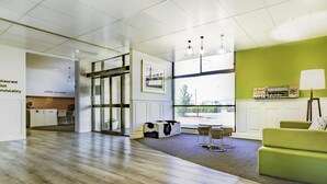 Un intérieur moderne avec un plancher en bois, un canapé vert, une table avec des chaises, un réfrigérateur et une fenêtre donnant sur un beau paysage.