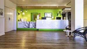 Un espace d’accueil doté d’un plancher en bois, d’un comptoir de réception et d’un mur d’accent de couleur verte.