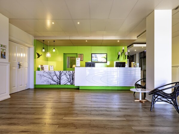 A reception area with a wooden floor, a reception desk, and a green accent wall.
