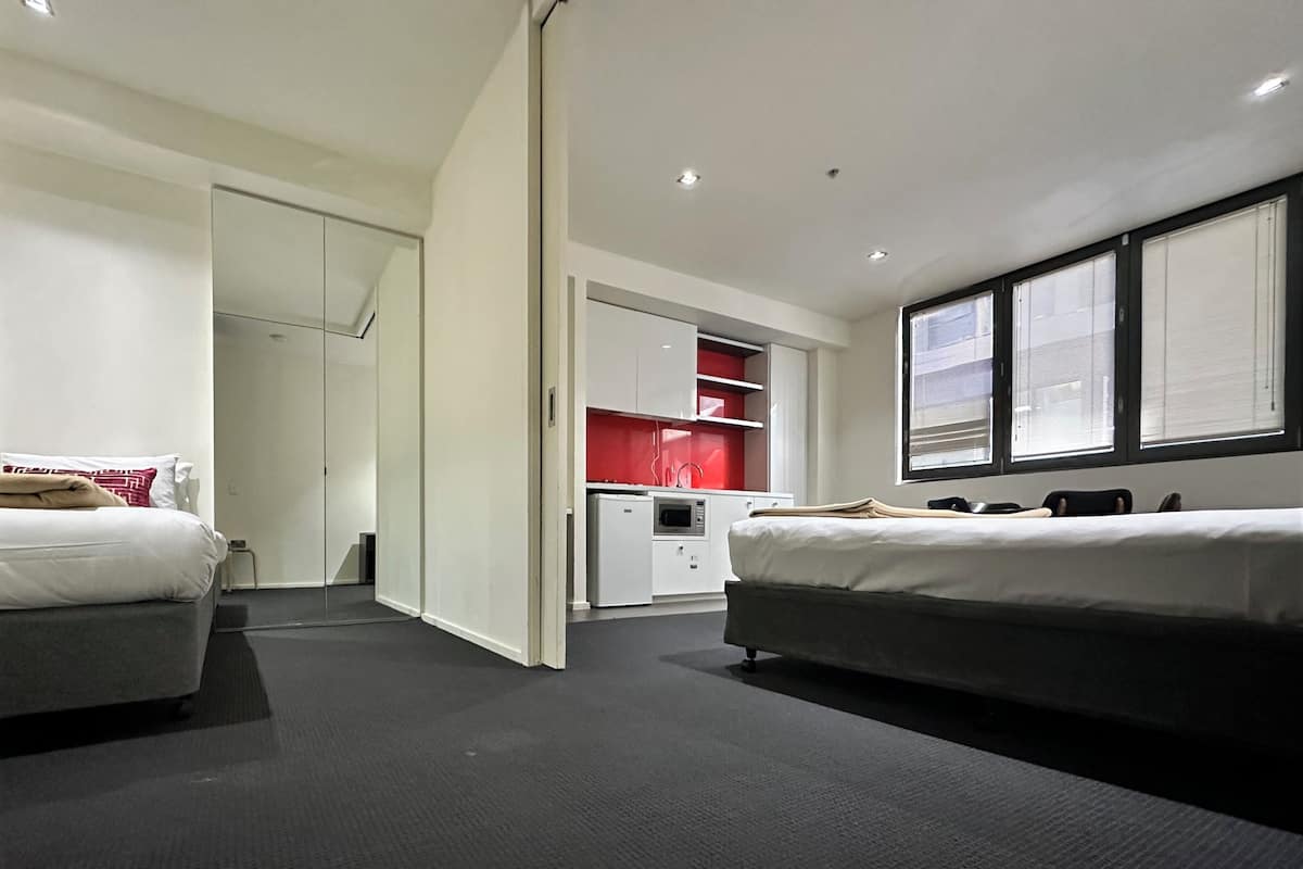 Une chambre d’hôtel moderne équipée de deux lits, d’une kitchenette et d’un placard.