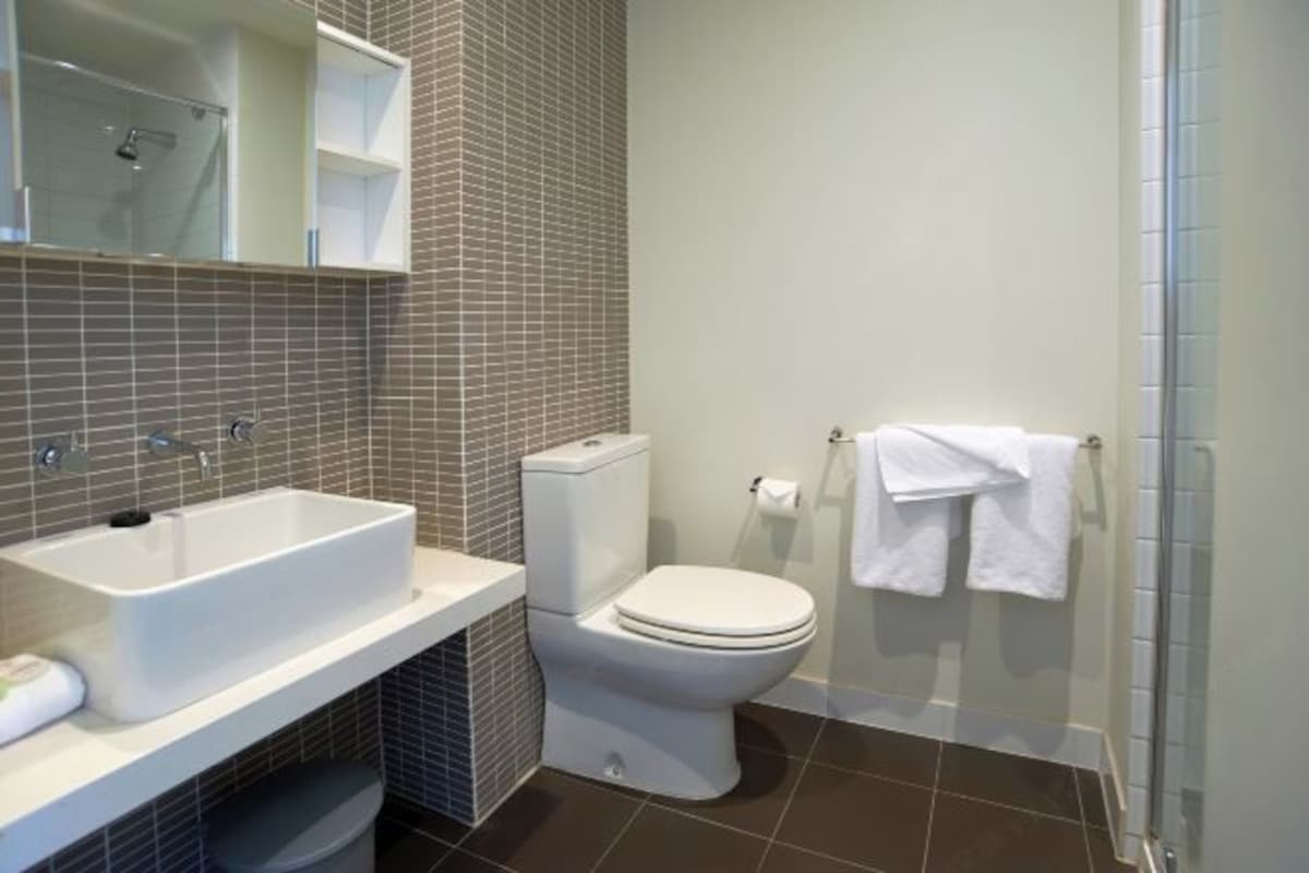 A modern bathroom with a white sink, toilet, and shower area.