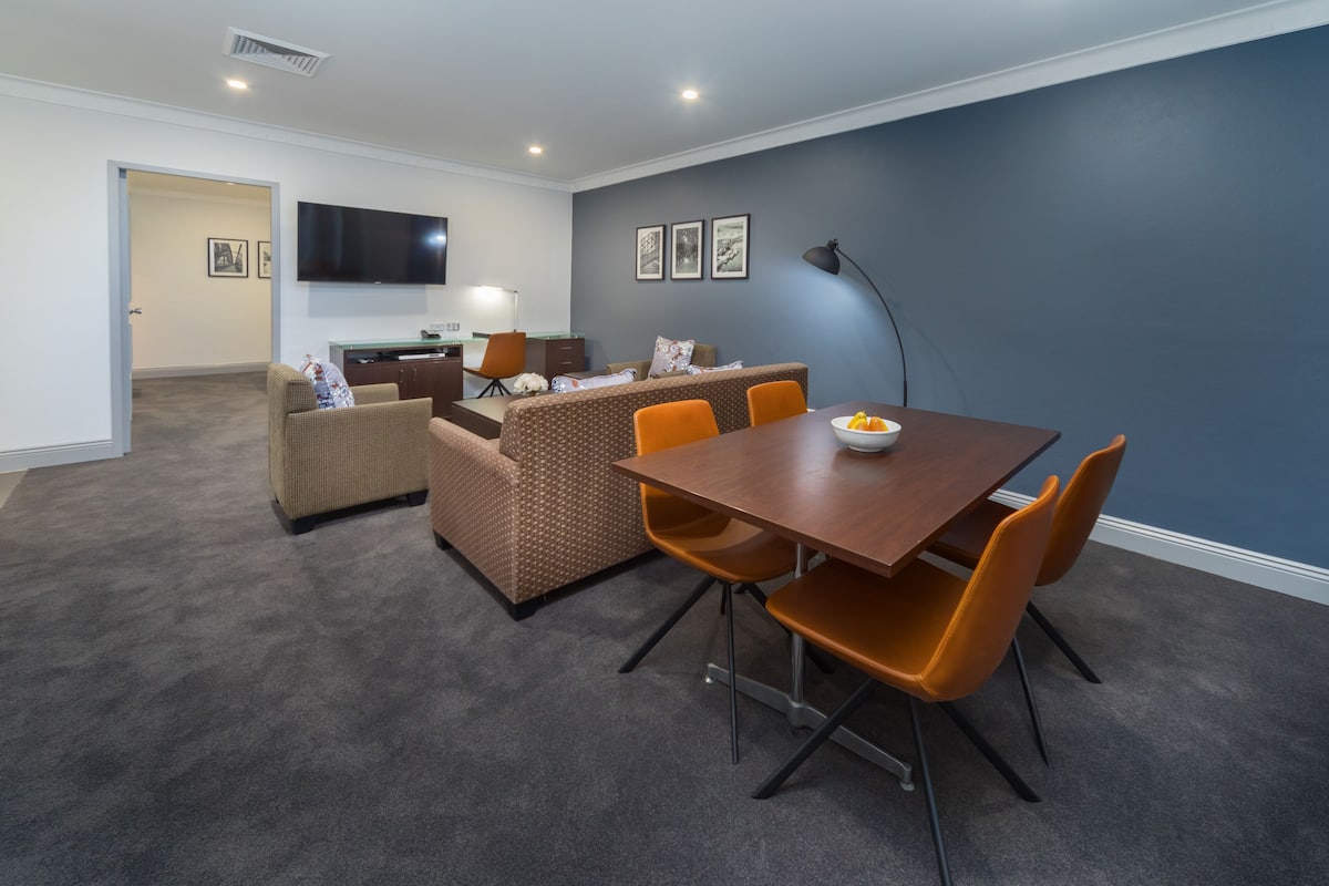 A modern living room with a dining area, a sofa, a TV, and a lamp.