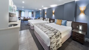 Una habitación de hotel con dos camas, kitchenette, zona de estar y baño.