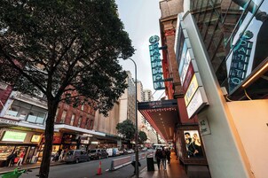 Un teatro con un cartel luminoso y un árbol en primer plano.