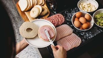 Bandeja de café da manhã com bagels, presunto fatiado, ovos, queijo e salsicha.