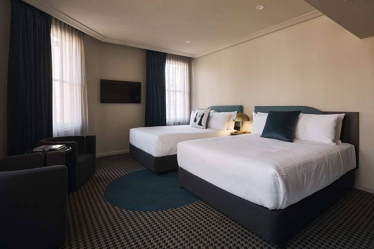 A hotel room with two beds, a TV, a desk, and a chair.