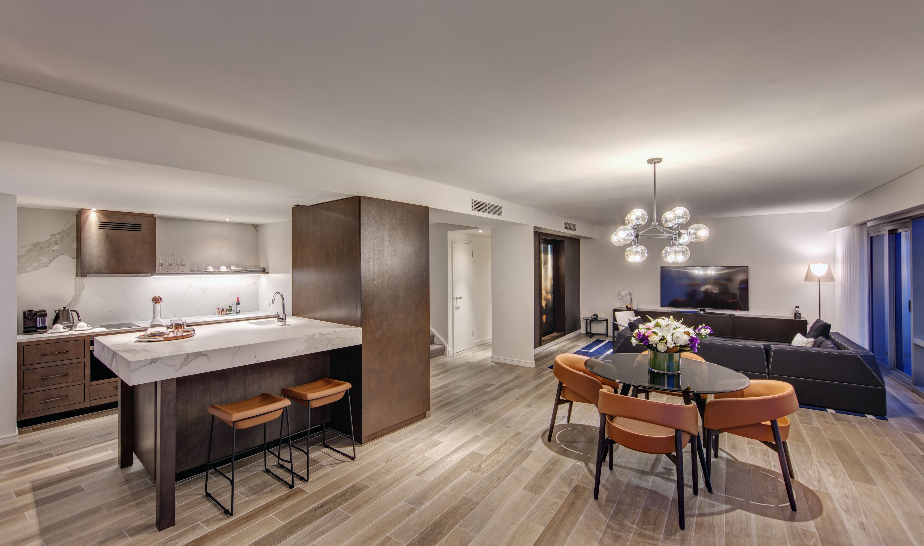 A modern kitchen with a central island, bar stools, and a dining area with a round table and chairs.