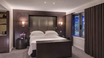 A modern hotel room with a large bed, bedside lamps, a nightstand, and a view of the city at night.