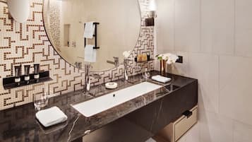 A modern bathroom with a large mirror, two sinks, a vanity, and a patterned tile backsplash.