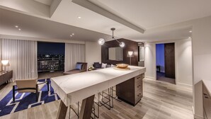 A modern hotel room with a large central island, a balcony with a city view, and a contemporary design.