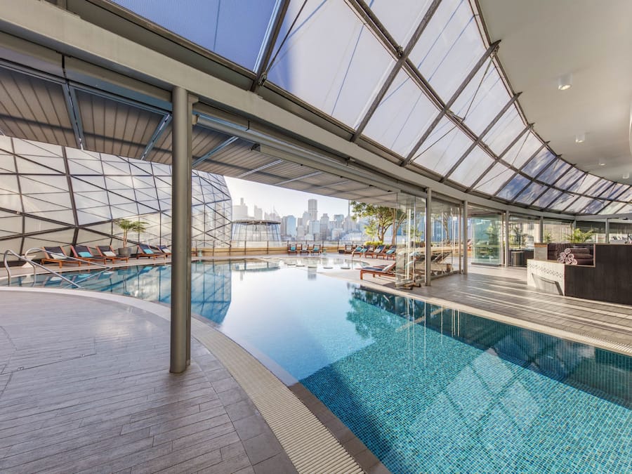 Una piscina al aire libre, sombrillas, sillones reclinables de piscina