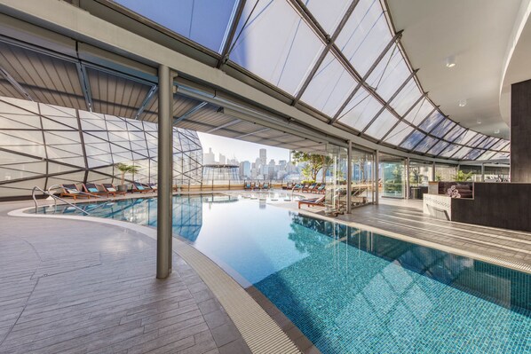 Una piscina al aire libre, sombrillas, sillones reclinables de piscina