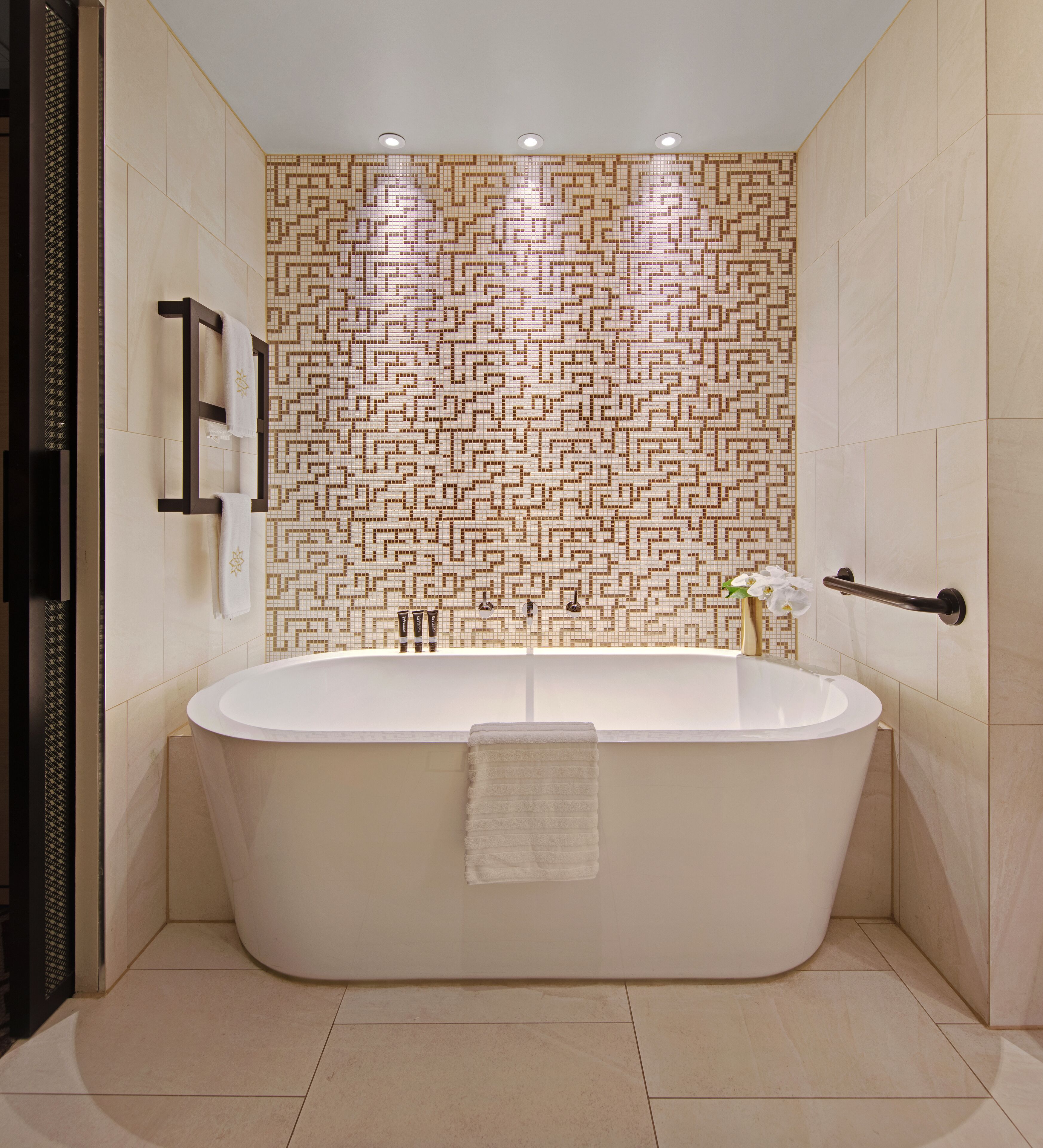 Une salle de bain moderne avec une baignoire sur pieds, un porte-serviettes et un mur décoré d’un motif.
