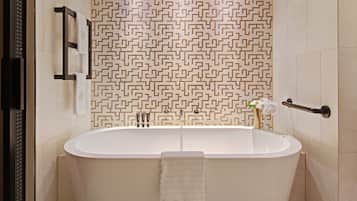 A modern bathroom with a freestanding bathtub, a towel rack, and a patterned wall.