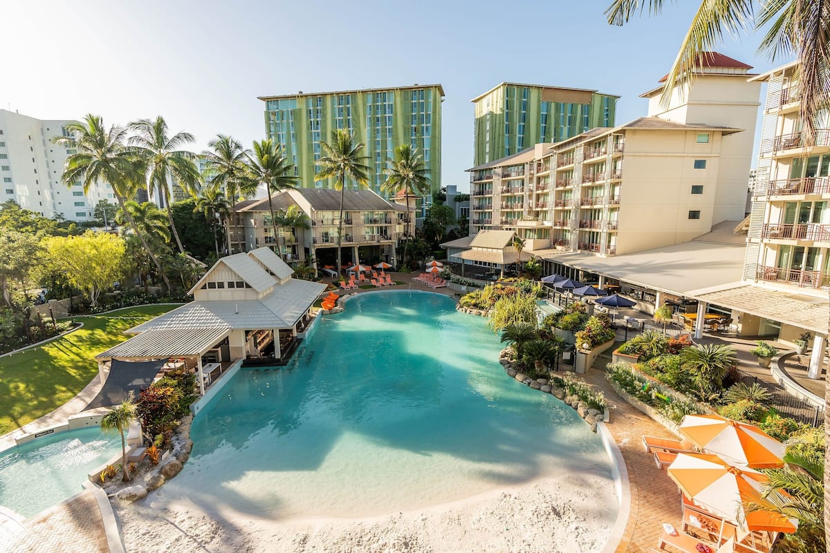 A resort with a large pool, multiple buildings, and palm trees.