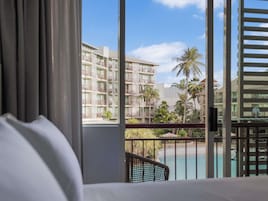 Habitación de hotel con vista a una piscina y un edificio con balcones.