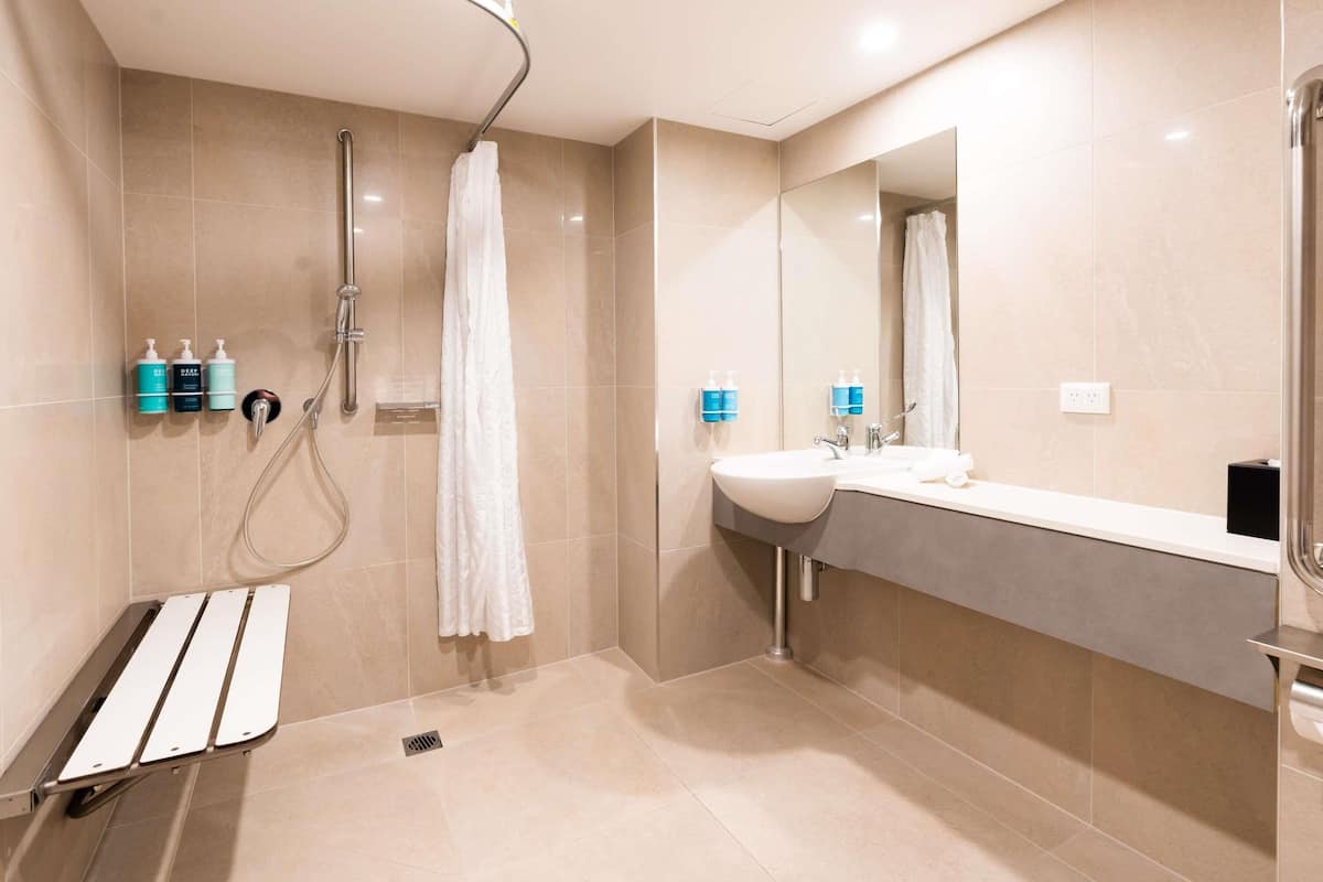 A modern bathroom with a curved shower, a sink with a mirror, and toiletries on the wall.