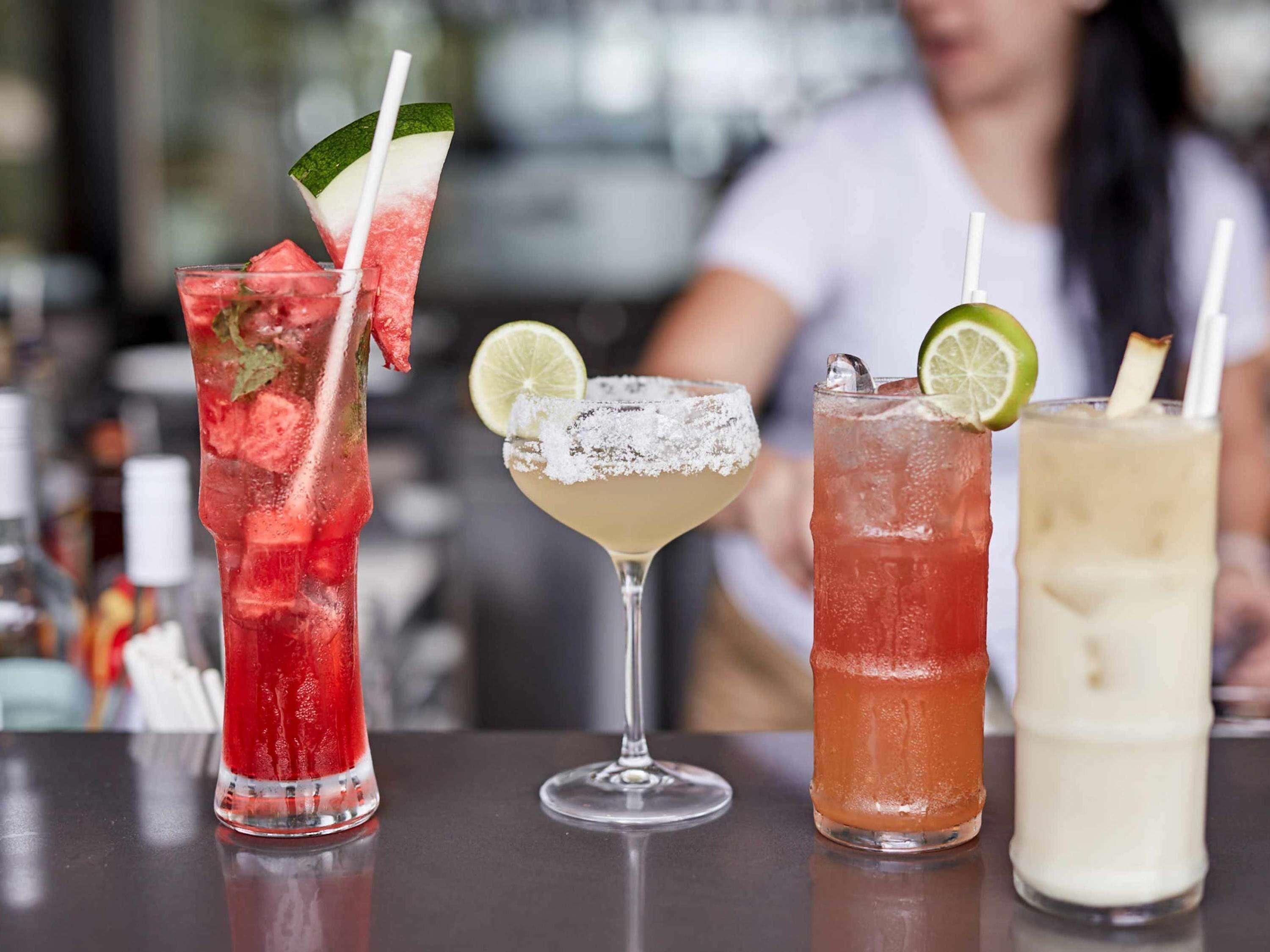 Four different cocktails on a bar counter with a blurred background.