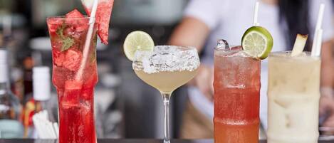 Four different cocktails on a bar counter with a blurred background.