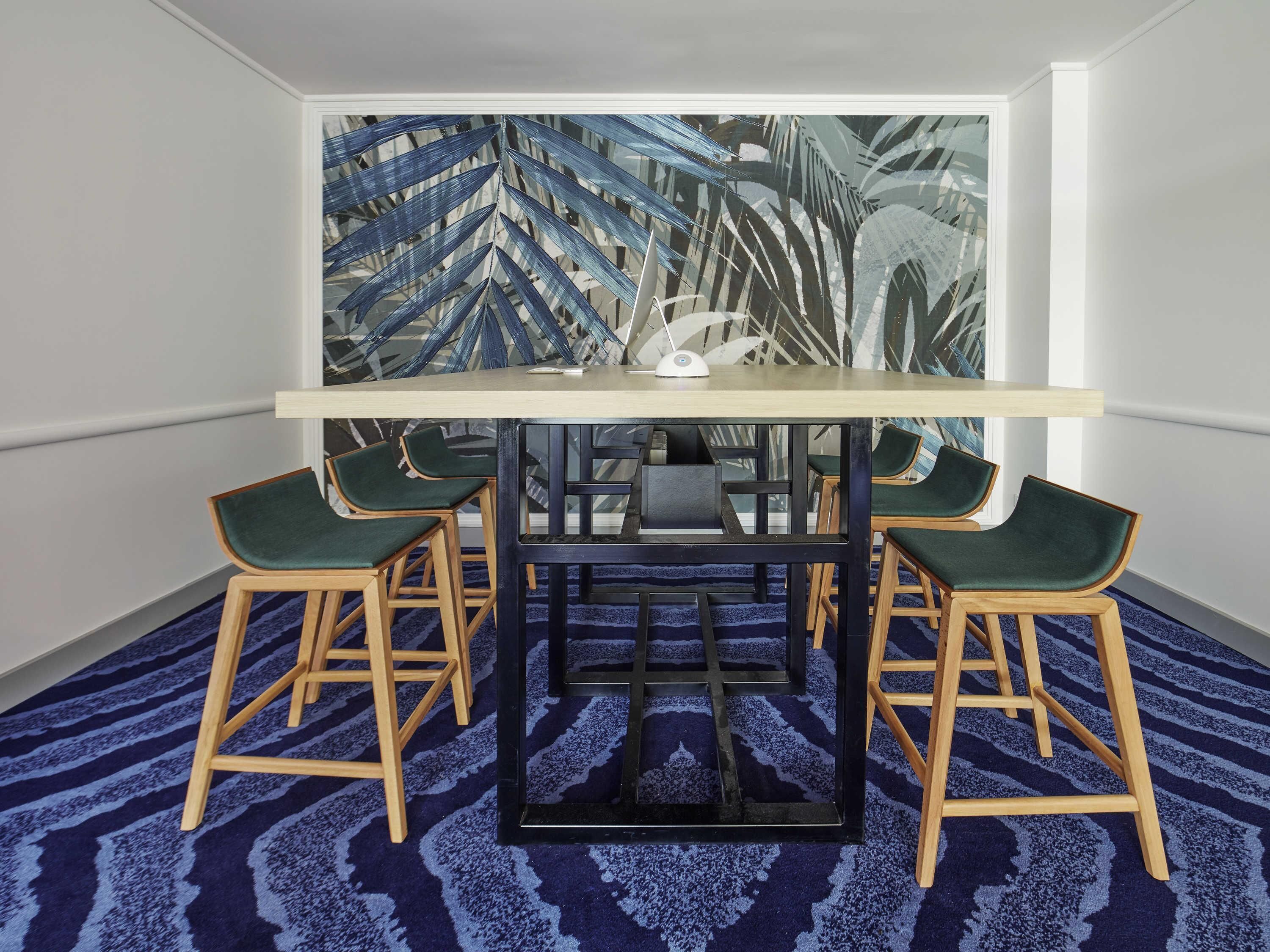 A room with a table and four chairs, a patterned carpet, and a large abstract painting on the wall.