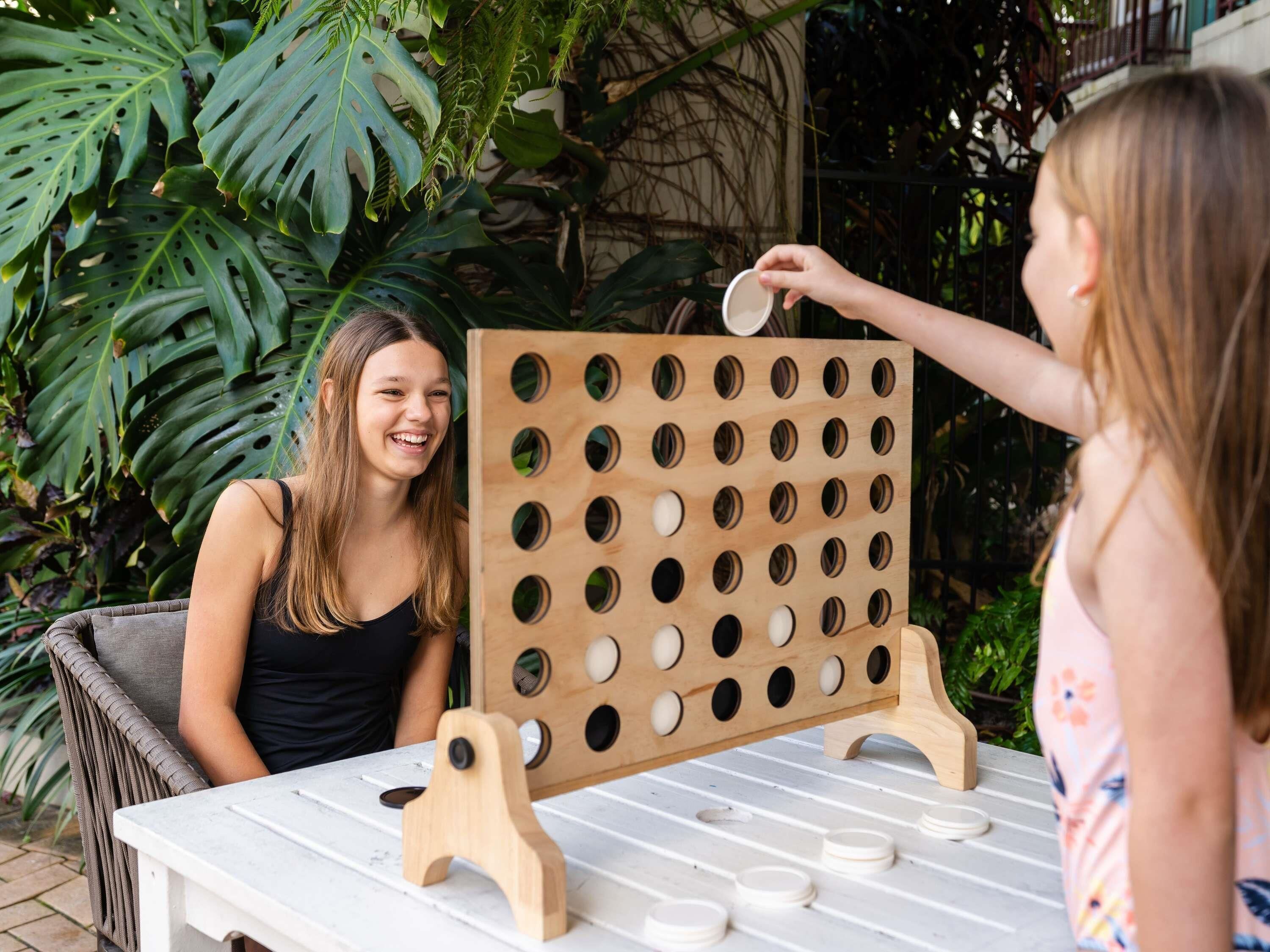Un juego de tablero con fichas de madera, instalado al aire libre, con una mesa y sillas.
