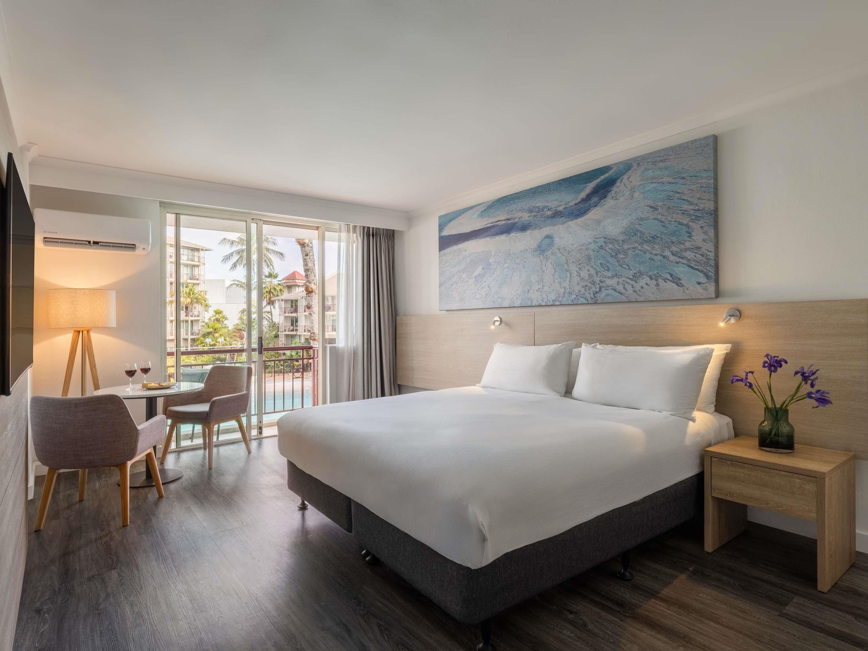 A hotel room with a bed, a desk, a chair, a nightstand, and a painting.