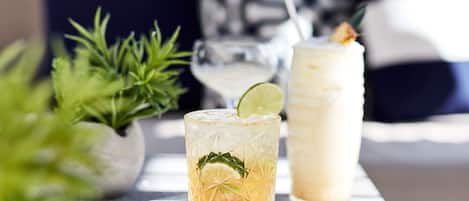 A table with two drinks, a plant, and a menu.