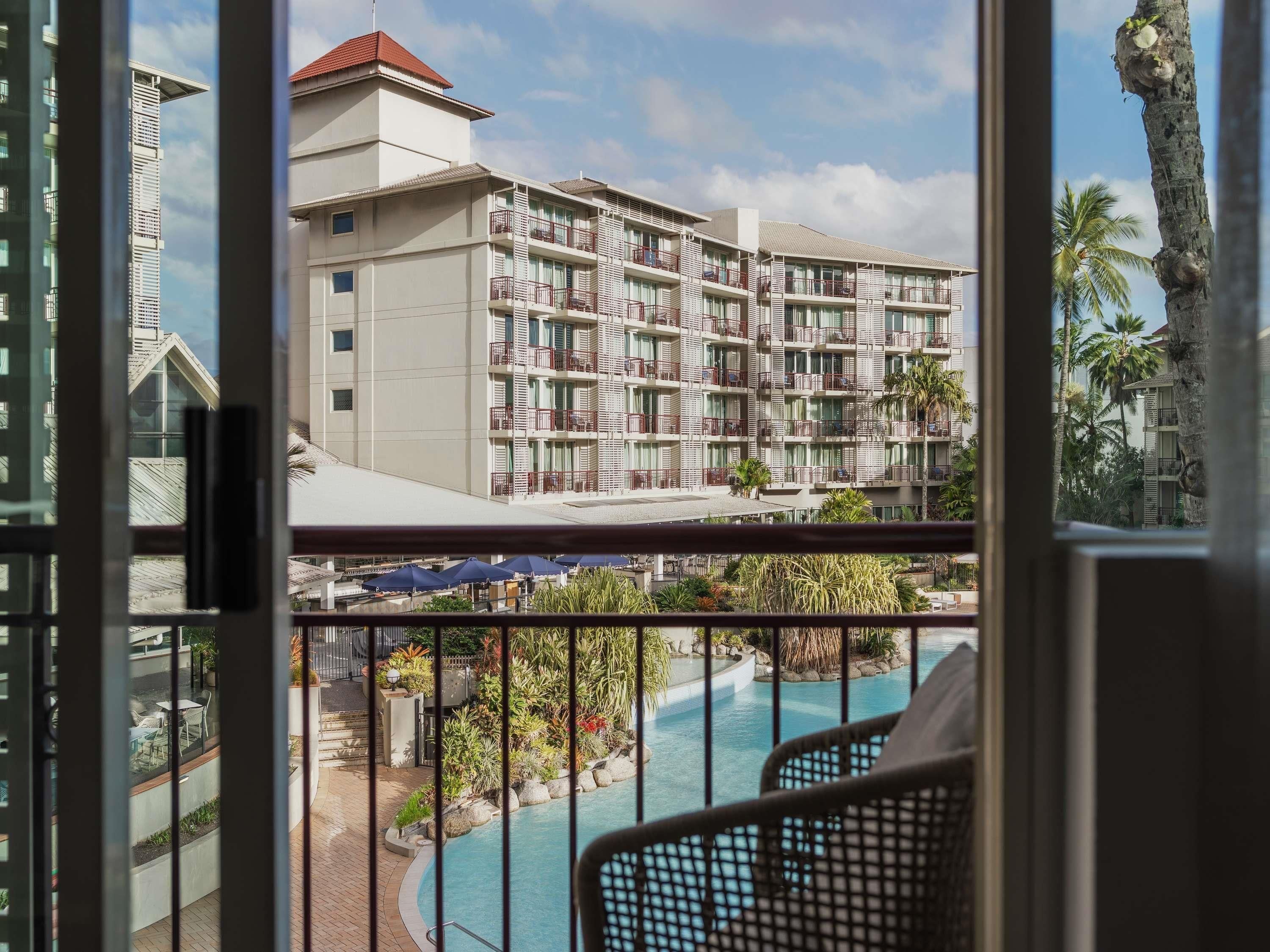 A hotel with a pool, outdoor seating, and a view of a palm tree.
