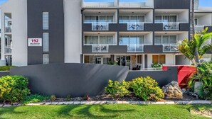 Un hotel de varios pisos con diseño moderno, que cuenta con balcones en cada planta, una entrada destacada y un jardín ajardinado.