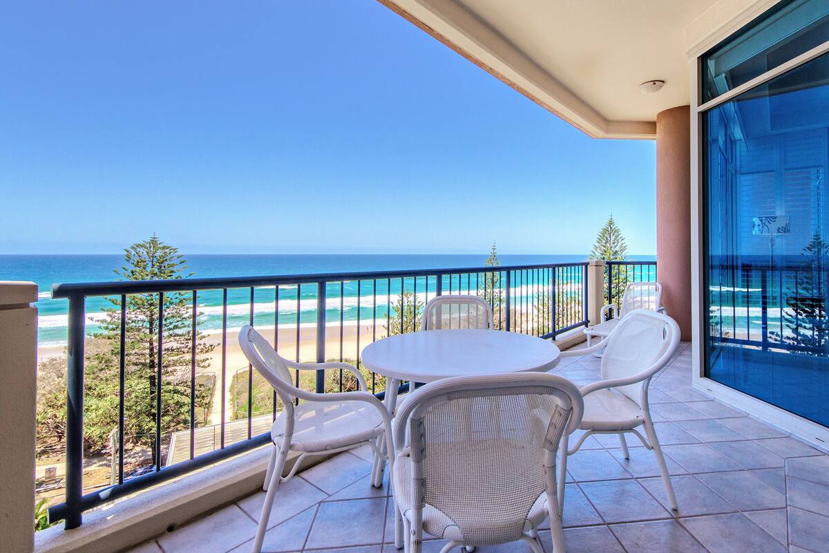 A balcony with a view of the beach and ocean.