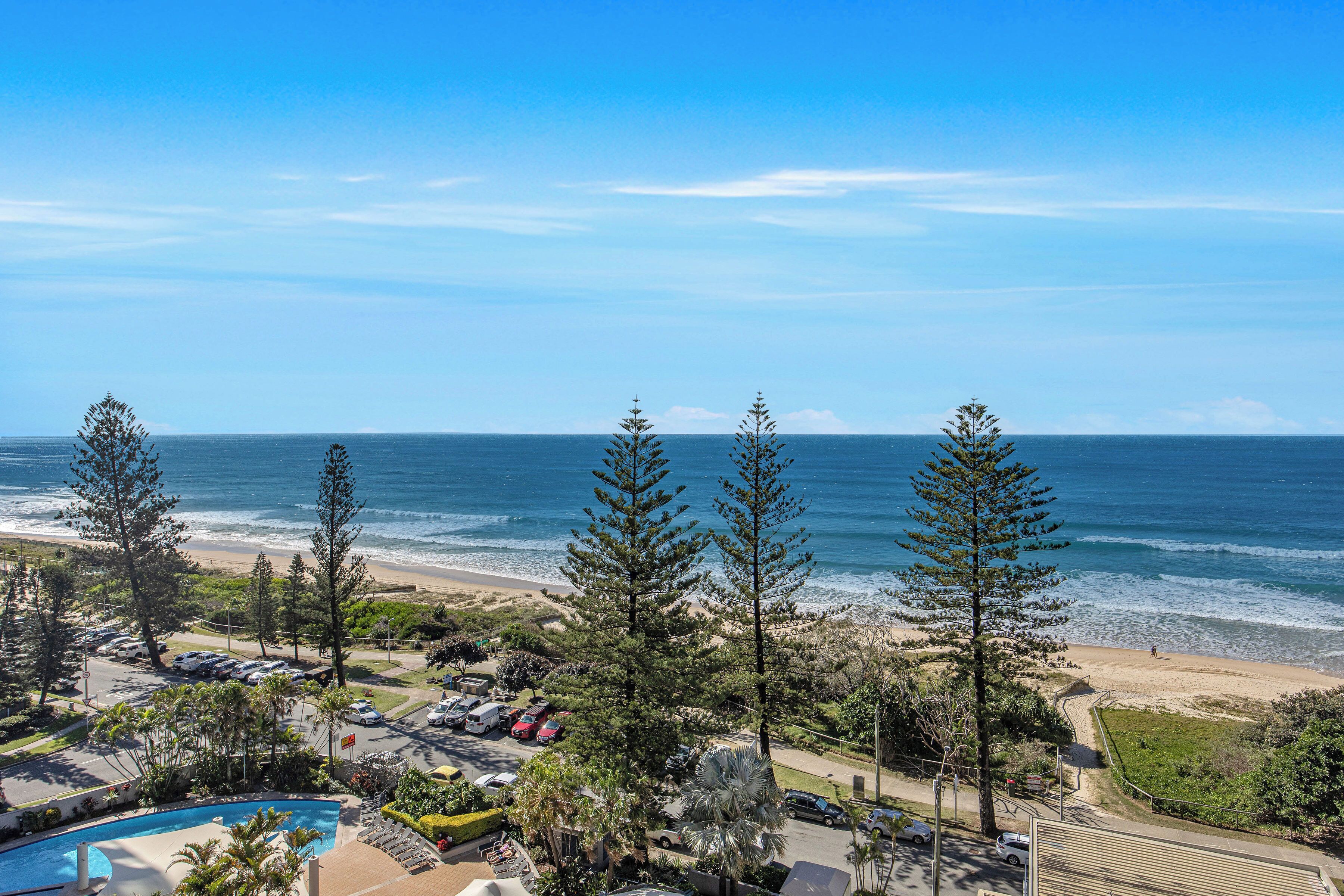 Un resort con piscina, vistas a la playa y zona de estacionamiento.