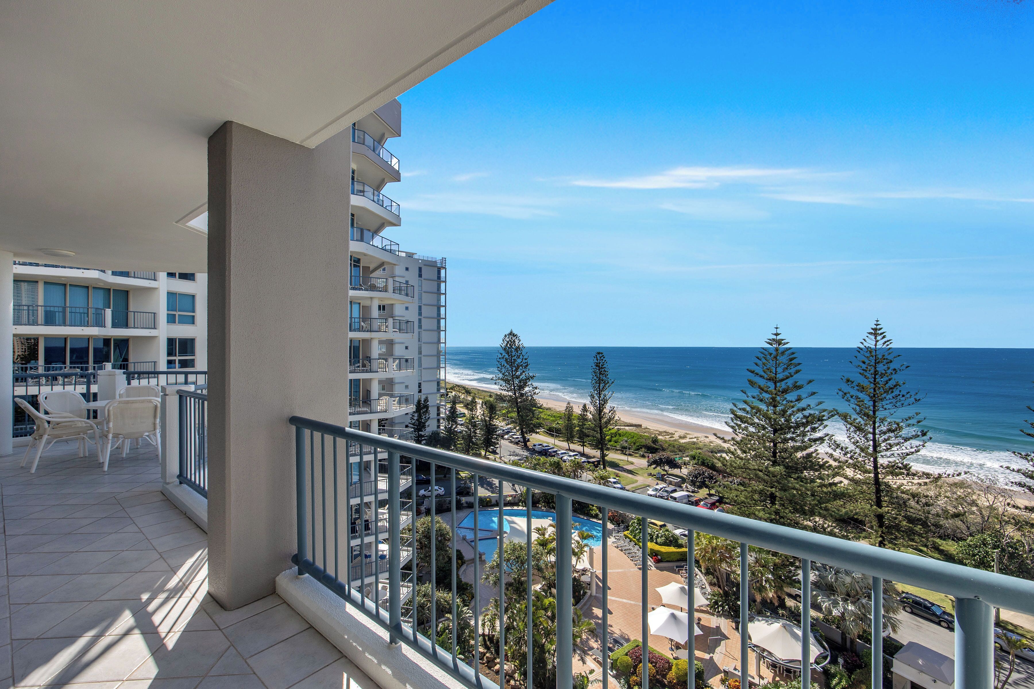 Ein Balkon mit Blick auf Strand und Meer, ein Poolbereich und eine Essgegend mit Gartenmöbeln.