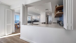 A modern kitchen with a central island, white cabinetry, and a view to the dining area.