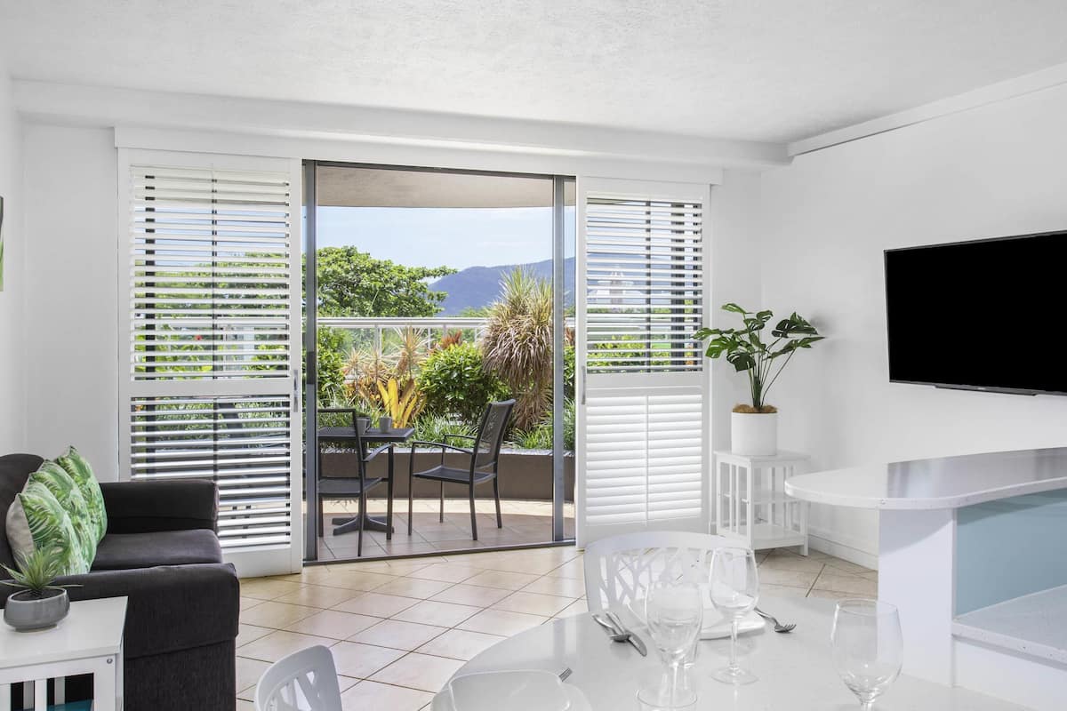 Un salón moderno con balcón, un televisor de pantalla plana y una zona de comedor para dos.