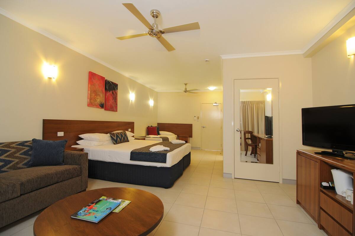 A hotel room with a bed, a sofa, a TV, and a ceiling fan.