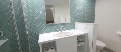 A bathroom with a white sink, mirror, and toilet.