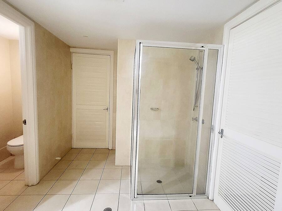 Ein Badezimmer mit Toilette, einer Dusche mit Glastür und einem gefliesten Boden.