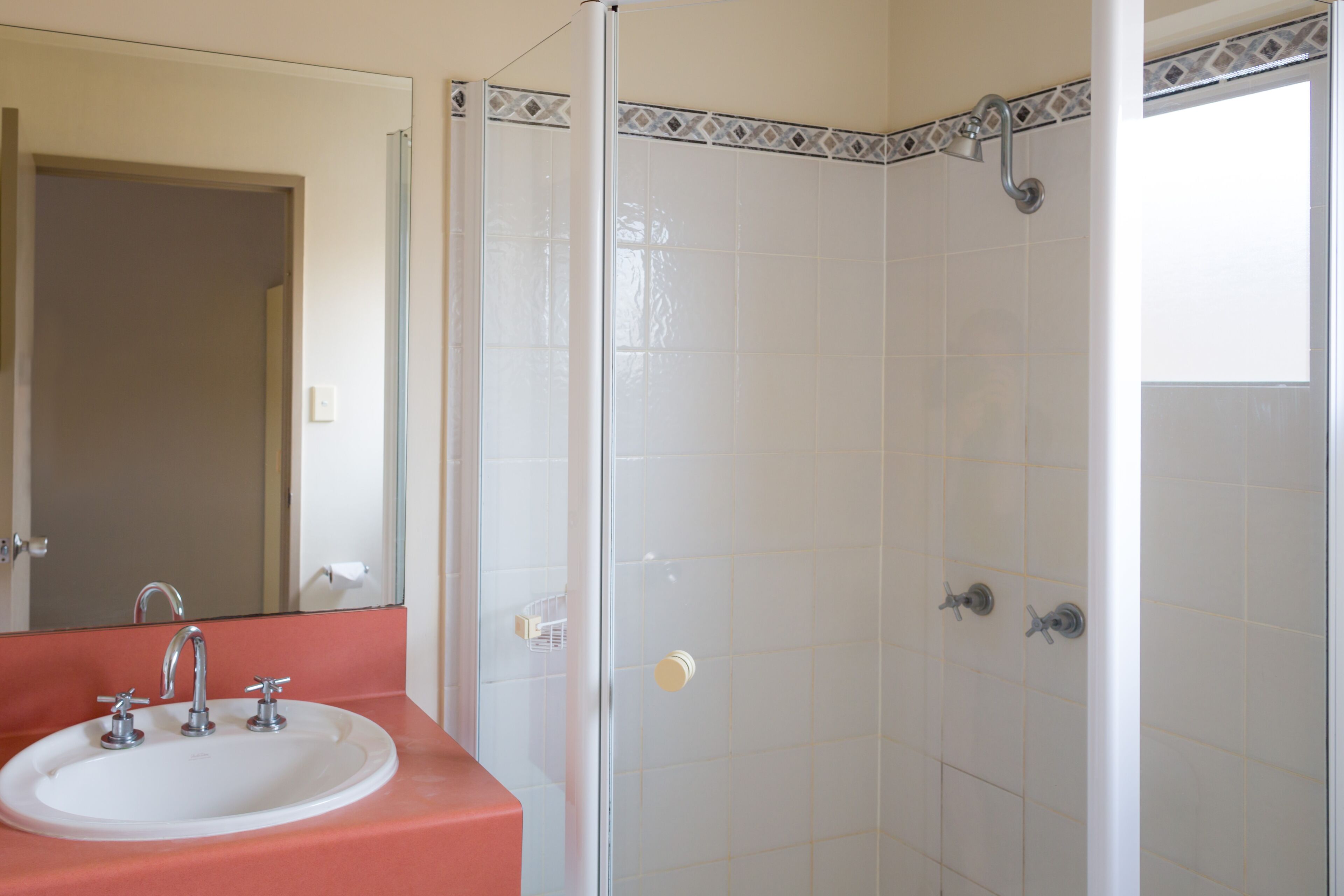 Un baño con lavamanos, espejo y ducha.